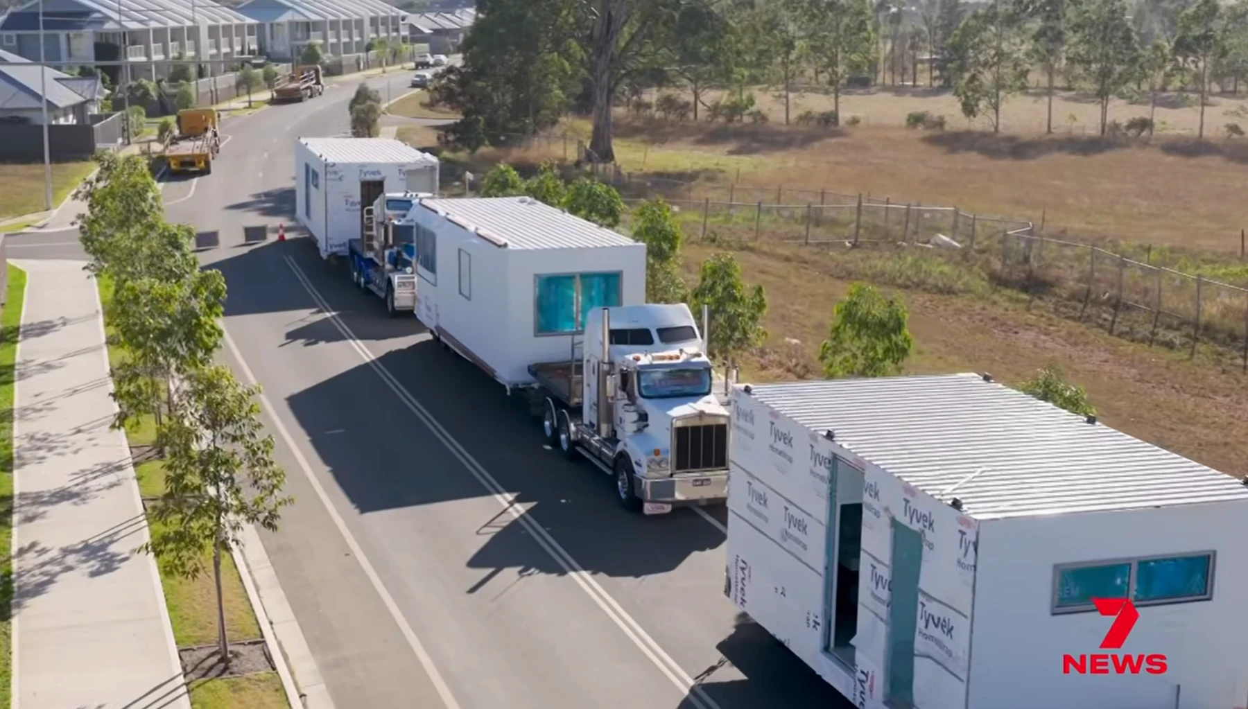 Trucks transporting prefabricated house modules along a residential street, from 7NEWS
